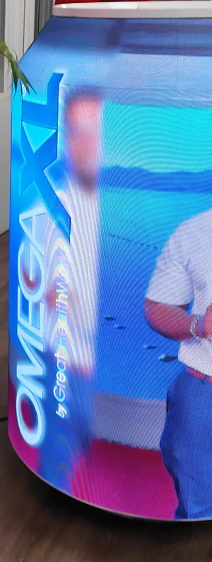 Lit Timesquare LED can running OmegaXL creative, the OmegaXL logo down its side, at an indoor match-night event