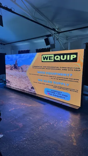 The eight-screen Timesquare P2.5 LED wall seen at an angle in the showroom, spliced into one canvas and running a WeQuip construction equipment ad