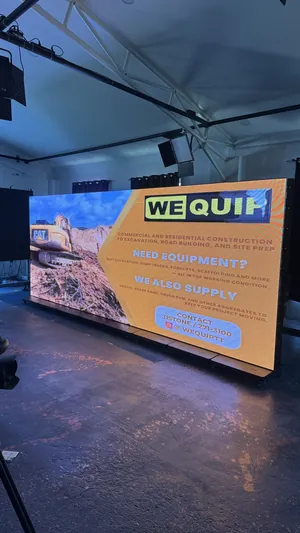 Looking down the length of the Timesquare LED wall, standing on its row of floor bases, with a WeQuip ad lit across all eight screens